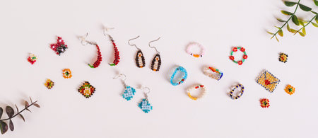 Earrings, rings and toys woven from multi-colored beads on a pink background top view web bannerの写真素材