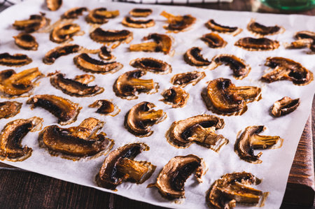Baked spicy mushroom chips on paper on a wooden board