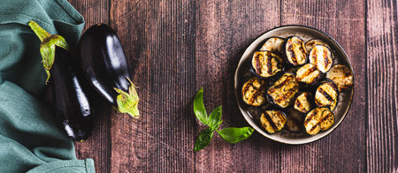 Delicious pieces of grilled eggplant on a plate on the table top view web bannerの写真素材