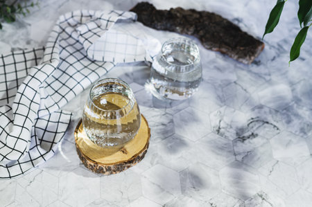 Clear transparent water in glasses in natural background with shadows and leavesの写真素材