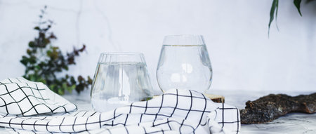 Clean organic water in glasses on table against background in shadows web banner