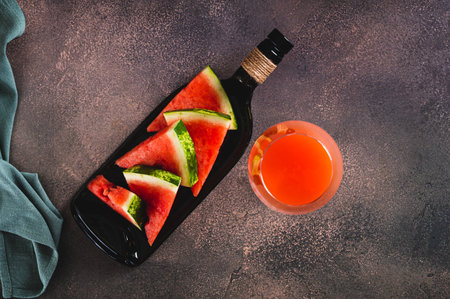 Close up of delicious watermelon wine in a glass and watermelon pieces on a plate top viewの写真素材