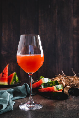 Delicious watermelon wine in a glass and watermelon pieces on a plate vertical viewの写真素材