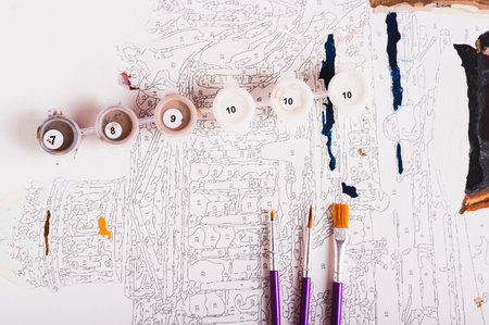 Several containers of paints and brushes on a painting by numbers, top viewの写真素材