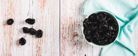 Blue bowl with natural organic prunes on table top view web banner