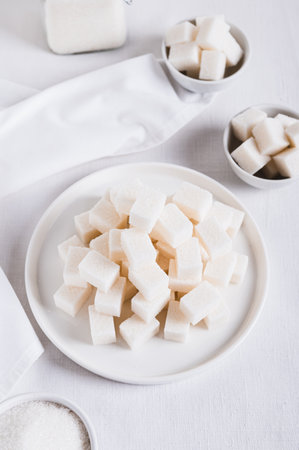 Alternative choice between lump sugar and granulated sugar on white background vertical viewの写真素材