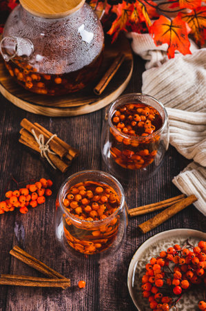 Warming rowan tea with cinnamon in glasses and a teapot on the table vertical viewの写真素材