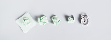 Burnout breaks concept. Crumpled note papers and alarm clock top view web banner