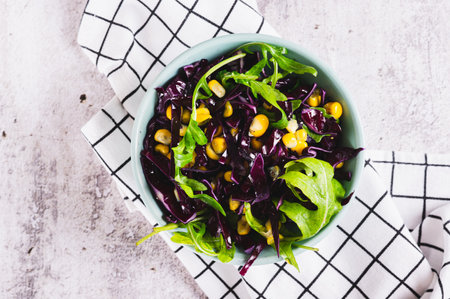 Close up of red cabbage, corn and arugula salad in a bowl on the table top viewの写真素材