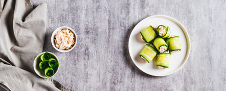Cucumber rolls with fish salad on a plate on the table top view web bannerの写真素材