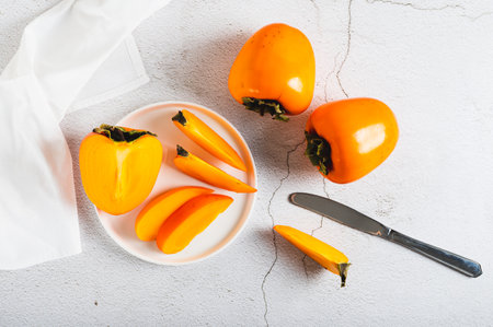 Sliced ââripe fresh persimmon on a plate on a table top viewの写真素材