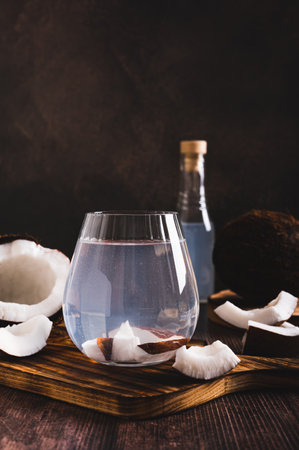 Fresh coconut water in a glass and coconut pieces on the table vertical viewの写真素材