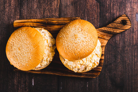 Close up of burgers with egg, tomato, cheese and garlic salad on a board on a table top viewの写真素材
