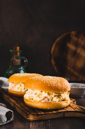 Hearty burgers with egg, tomato, cheese and garlic salad on a board on a table vertical viewの写真素材