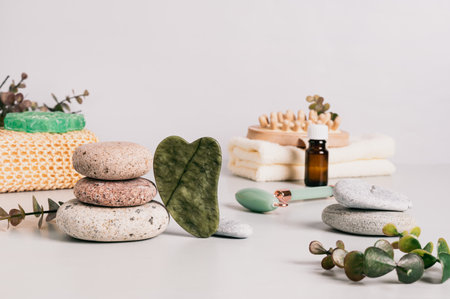 Jade gua sha massager, pebbles and spa items on tableの写真素材