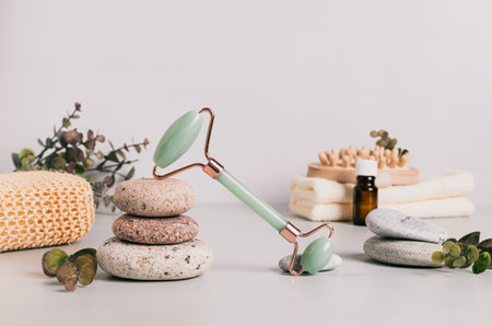 Jade facial massager, spa items and pebbles on tableの写真素材