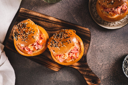 Baked burgers with sausages, tomatoes, cheese and egg on a board on a table top viewの写真素材