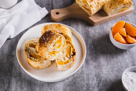 Delicious roll with tangerine on a plate on the table