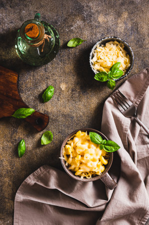 Cup with baked macaroni cheese and basil on the table top and vertical viewの写真素材