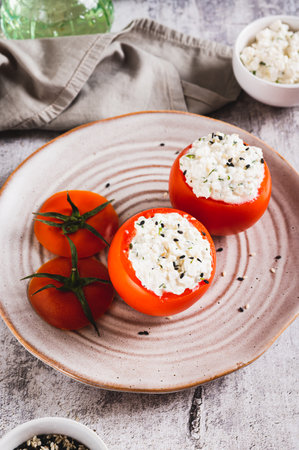 Tomatoes stuffed with cottage cheese and dill on a plate on the table vertical viewの写真素材