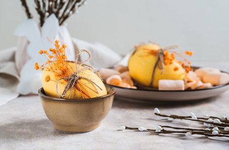 Easter egg with dried flowers in a bowl and pussy willow on the table