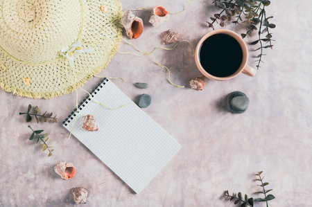 Travel planning notebook, hat, seashells and cup of coffee on table top viewの写真素材