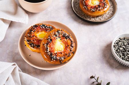 Egg with tomato and sesame seeds baked in bagels on a plate on the table