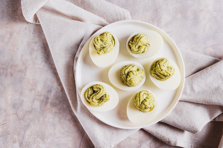 Close up of eggs stuffed with avocado and yolk mixture on a plate on a table top view