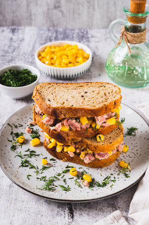 Tuna and corn salad on grain bread on a plate on a table vertical viewの写真素材