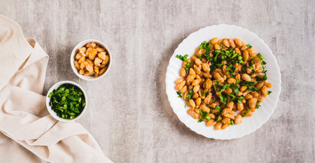 Homemade fried white beans and greens salad on plate on table top view web banner