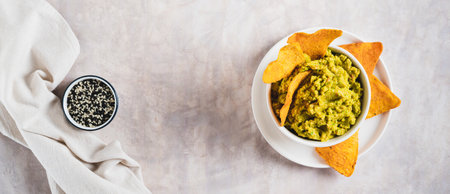 Delicious guacamole in a bowl and tortilla chips on a plate on the table top view web bannerの写真素材