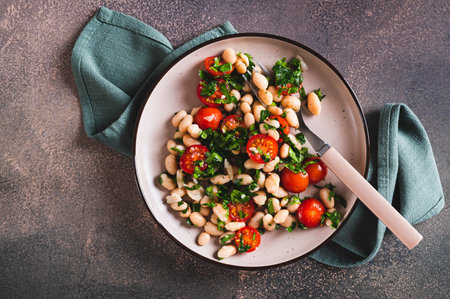 Close up of appetizing salad of white beans, cherry tomatoes and parsley on a plate top viewの写真素材
