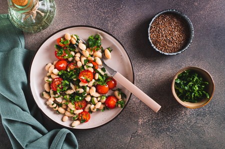 Appetizing salad of white beans, cherry tomatoes and parsley on a plate top viewの写真素材