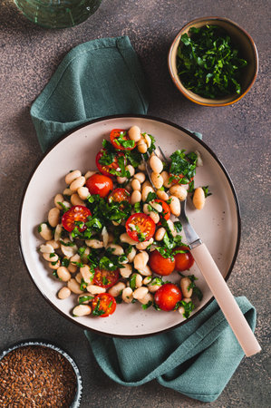 Vegetarian white bean, tomato and herb salad on a plate on the table top and vertical viewの写真素材