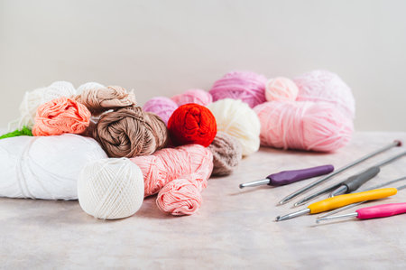 Lots of colorful skeins of yarn, crochet hooks and knitting needles on a table