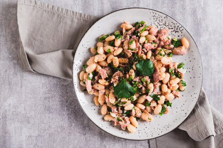 Close up of appetizing salad with tuna, white beans and greens on a plate on the table top viewの写真素材