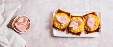 Pineapple and prosciutto tarts on a plate on a table top view web banner