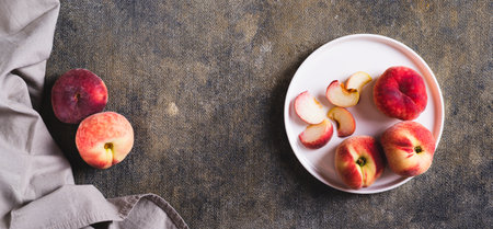 Fresh ripe sliced â€‹â€‹peaches and knife on plate on table top view web banner
