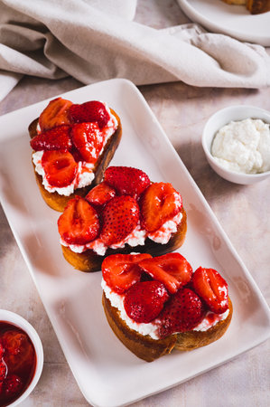 Sandwiches with cream cheese and fried strawberries on a plate on a table vertical viewの写真素材