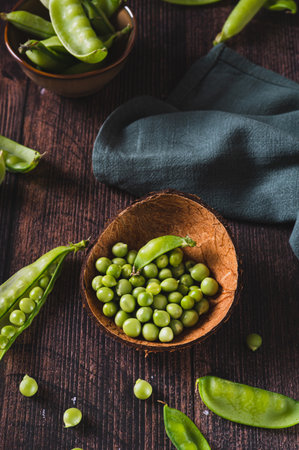 Bowl with green sugar peas on wooden table vertical viewの写真素材