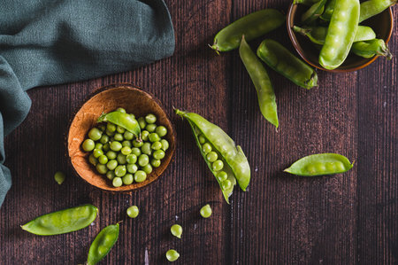 Fresh green peas in a bowl and in pods on the table top viewの写真素材