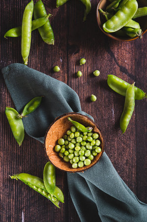 Bowl with green sugar peas on wooden table top and vertical viewの写真素材