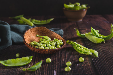 Fresh green peas in a bowl and in pods on the tableの写真素材