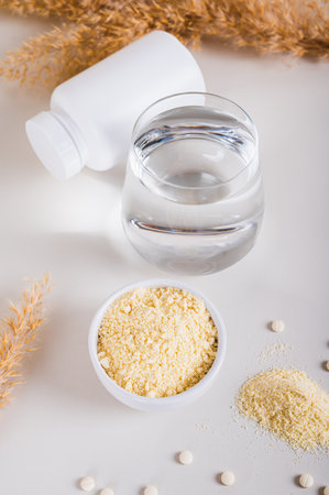 Health food with peptides and water in a glass on the table vertical view