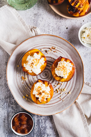 Grilled peaches with cottage cheese, nuts and honey on a plate top and vertical viewの写真素材