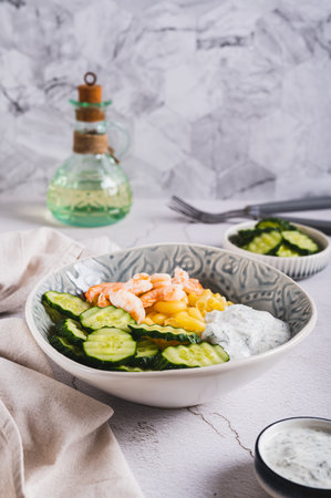 Bowl with pasta, shrimp, cucumber and sauce on the table vertical viewの写真素材