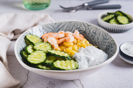 Bowl with pasta, shrimp, cucumber and sauce on the tableの写真素材
