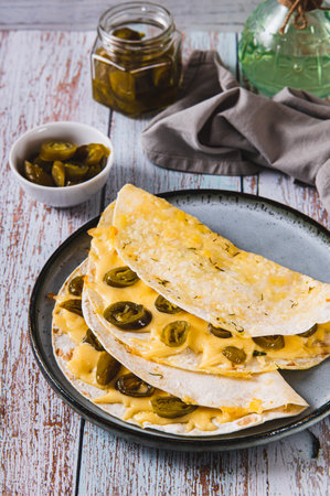 Cheese and jalapeno Mexican quesadillas on a plate on the table vertical view