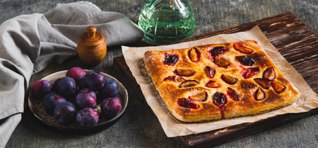 Sweet focaccia with plum on a wooden board on the table web bannerの写真素材