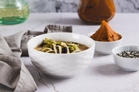 Delicious miso soup with noodles and broccoli in a bowl on the table